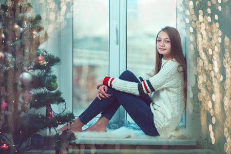 Young beautiful woman with reddish hair sitting home by the windowの写真素材