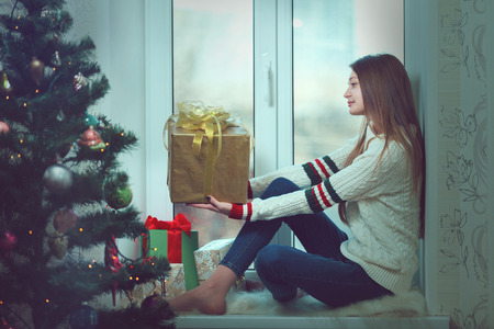 Young beautiful woman with reddish hair sitting home by the windowの写真素材