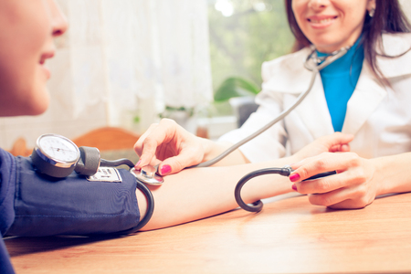 Beautiful young female doctor is checking the blood pressure of the patient.の写真素材