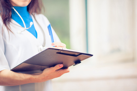 Close-up Of famale Doctor Filling The Medical Formの写真素材