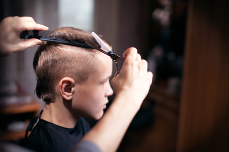 Beautiful young hairdresser giving a new haircut to male customer at parlorの写真素材
