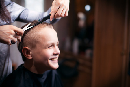 Beautiful young hairdresser giving a new haircut to male customer at parlorの写真素材