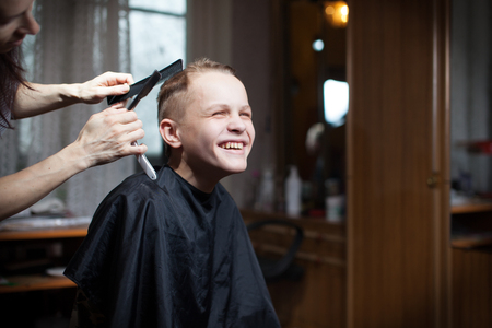 Beautiful young hairdresser giving a new haircut to male customer at parlorの写真素材