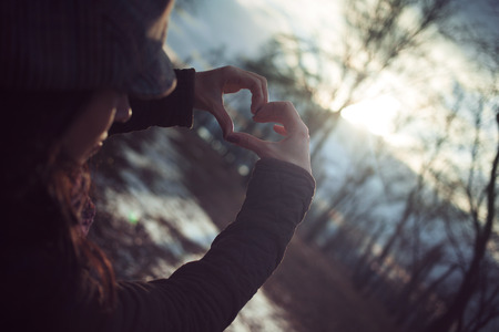 Female hands in the form of heart against the sky pass sun beams.の写真素材