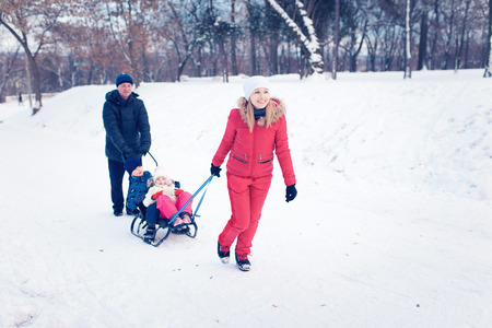 Young Family Running Through Snow With Sledの写真素材