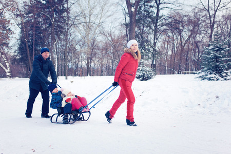Young Family Running Through Snow With Sledの写真素材