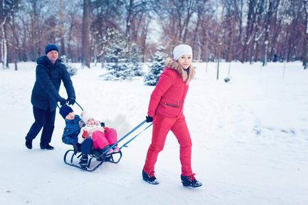 Young Family Running Through Snow With Sledの写真素材