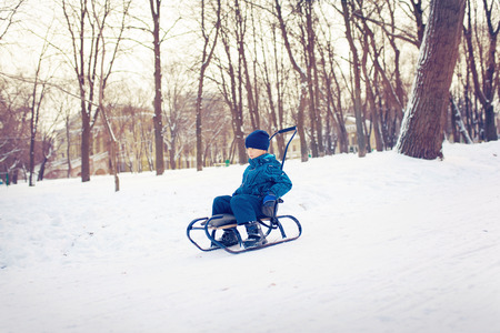 Cute young boy sprayed with snow as he is sledgingの写真素材