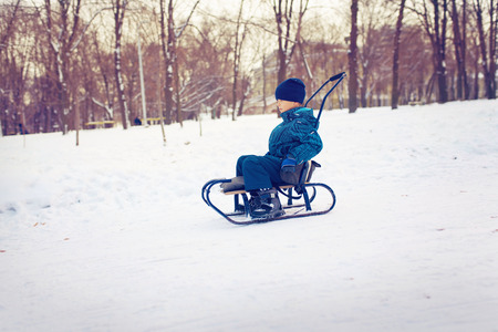 Cute young boy sprayed with snow as he is sledgingの写真素材