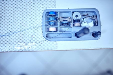 Workplace of tailor - sewing machine, rolls of of thread, fabric, scissors.