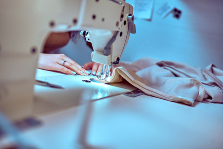 seamstress sews clothes. Workplace of tailor - sewing machine, rolls of thread, fabric, scissors.の写真素材