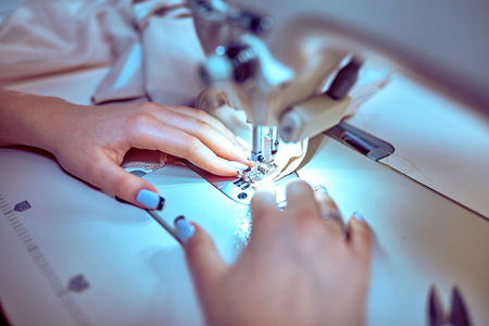 seamstress sews clothes. Workplace of tailor - sewing machine, rolls of thread, fabric, scissors.