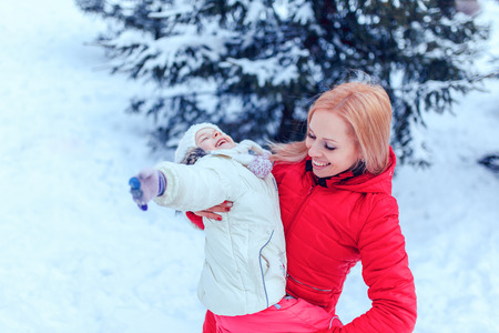 Mother and child girl having fun, playing and laughing on snowy winter walk in nature.の写真素材