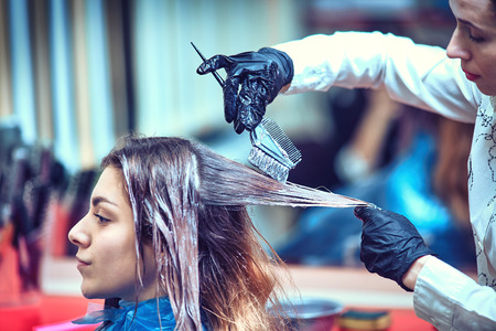 Professional hairdresser dyeing hair of her clientの写真素材