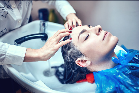 Close up of face of beautiful woman is getting a hairwash by a hairdresser.の写真素材