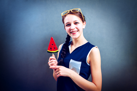 Funny girl eating lollipop on a blue background, studioの写真素材