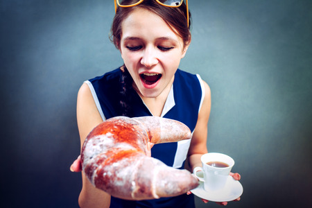 Beautiful young woman with tasty croissant and cup of coffee on  backgroundの写真素材