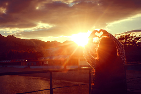 hands forming a heart shape with sunset silhouetteの写真素材