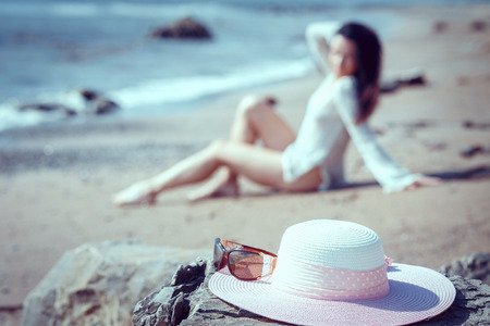 Girl with a hat hand on the beachの写真素材