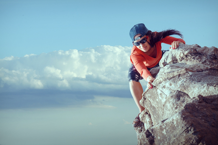 young girl tourist looks for way from the top of the rockの写真素材