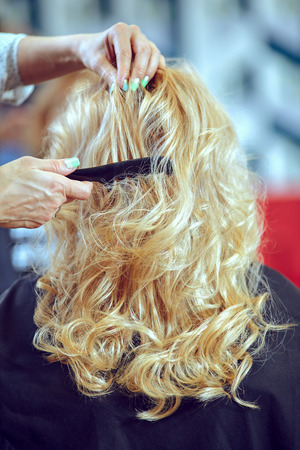 Young woman sitting while the hairdresser is styling her hair.の写真素材