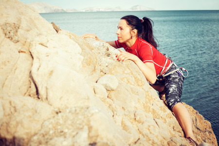 Young girl tourist looks for way from the top of the rockの写真素材