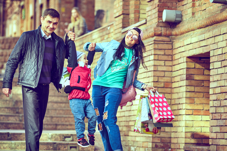 Young happy family of three having fun together outdoor. Pretty little daughter on her father back. Parents and girl look happy and smile. Happiness and harmony in family life. Family fun outside.の写真素材