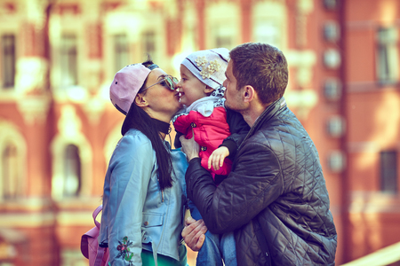 Young happy family of three having fun together outdoor. Pretty little daughter on her father back. Parents and girl look happy and smile. Happiness and harmony in family life. Family fun outside.の写真素材