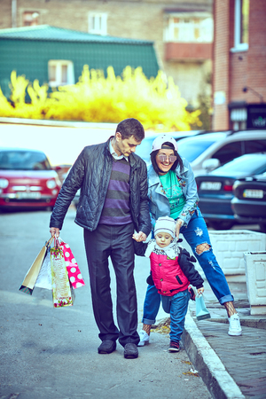 Young happy family of three having fun together outdoor. Pretty little daughter on her father back. Parents and girl look happy and smile. Happiness and harmony in family life. Family fun outside.の写真素材