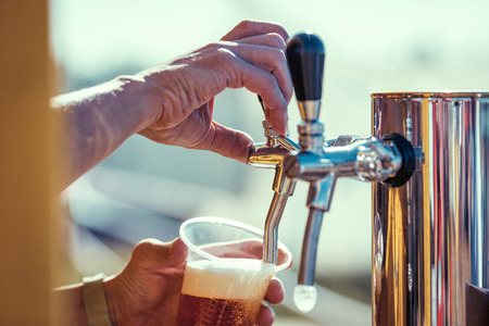 close-up of barman hand at beer tap pouring a draught lager beerの写真素材