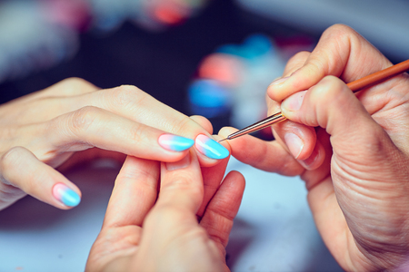 Side view of manicurist applying marsala nail polishの写真素材