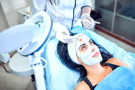 Cosmetologist makes the mask beautiful girlの写真素材