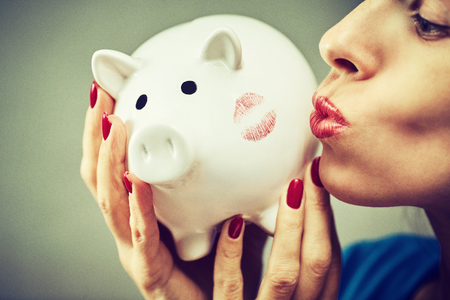 Glasses woman saving on eyewear showing piggy bankの写真素材