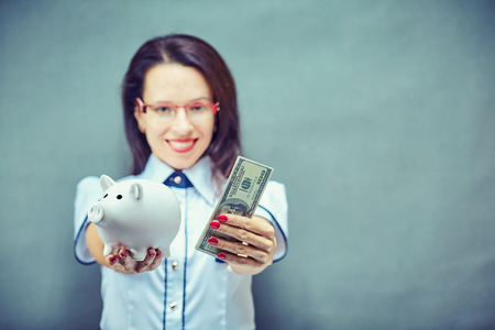 Glasses woman saving on eyewear showing piggy bankの写真素材