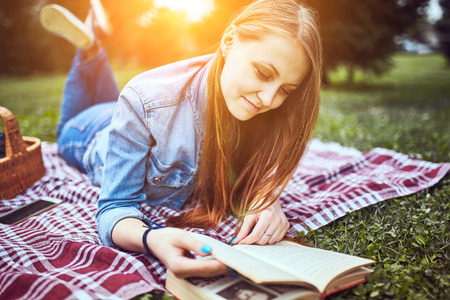 Young beautiful girl reading a book outdoorの写真素材