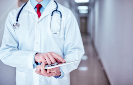 male doctor with tablet at the office, text messaging.の写真素材
