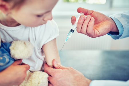 Doctor pediatrician injecting vaccine to cute  girlの写真素材