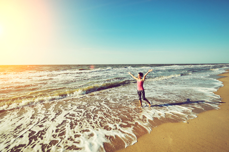 Freedom young woman with arms up outstretched to the sky with blue ocean landscape beach background copy space.の写真素材