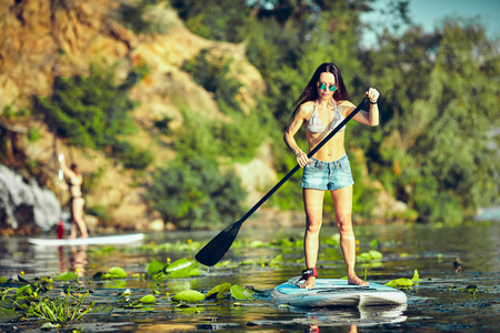 Attractive young woman stand up paddle surfingの写真素材