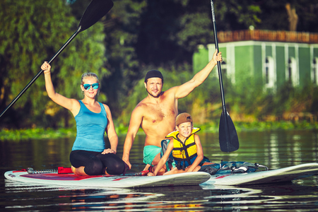 Family Having Fun Stand Up Paddling Together in the Ocean on Beautiful Sunny Morningの写真素材