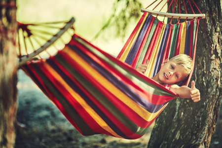 Funny little boy playing in hammock, child resting in gardenの写真素材