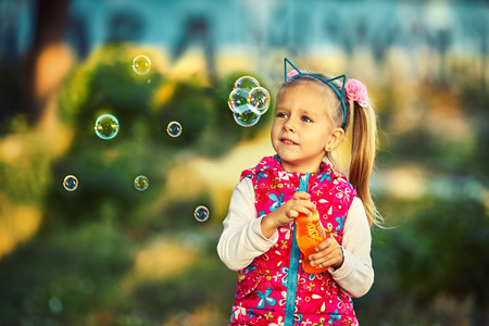 Pretty little girl blowing bubbles in the park.の写真素材