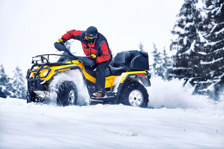 Rider driving in the quadbike race in winter in the forest