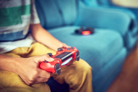 Hands using video game controller, on the couch at home