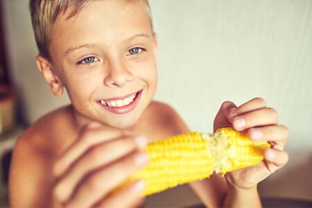 Happy boy with an appetite eating cornの写真素材