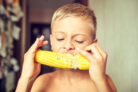 Happy boy with an appetite eating cornの写真素材