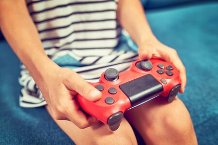 Hands using video game controller, on the couch at homeの写真素材