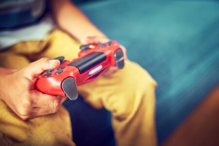 Hands using video game controller, on the couch at home