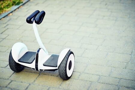 Teenager rides whirl on a hoverboard over park pathsの写真素材