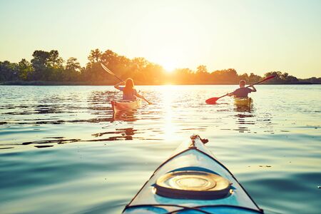 Kayaking couple ride along the river at sunsetの写真素材